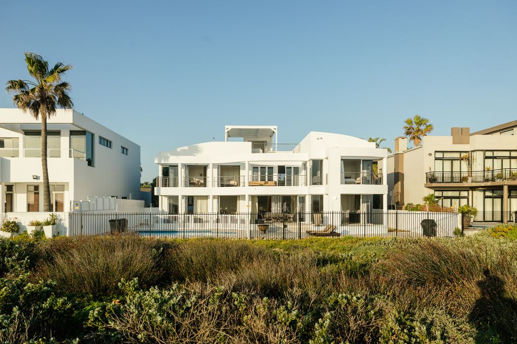 Modern white multi-story villa with balconies and pool