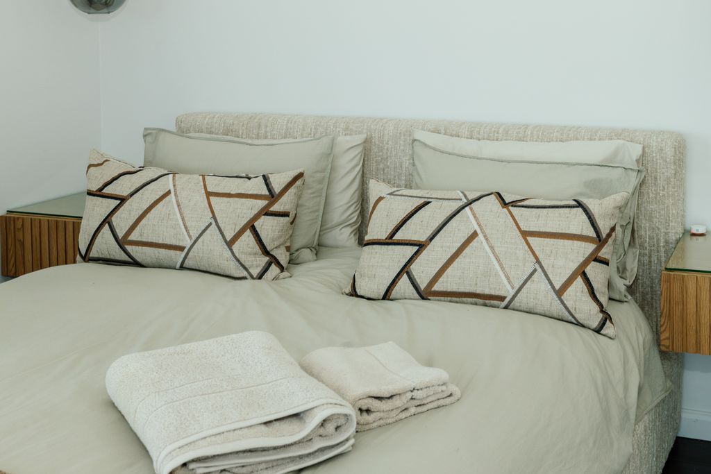Bed with geometric patterned pillows and folded towels