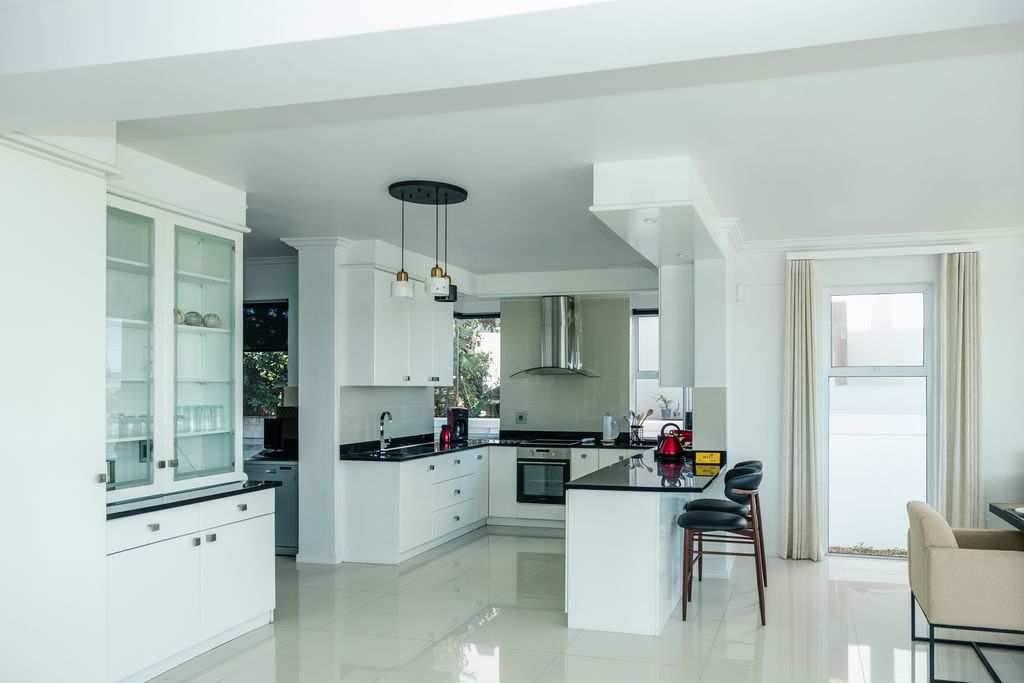 Modern white kitchen with black countertops and breakfast bar.