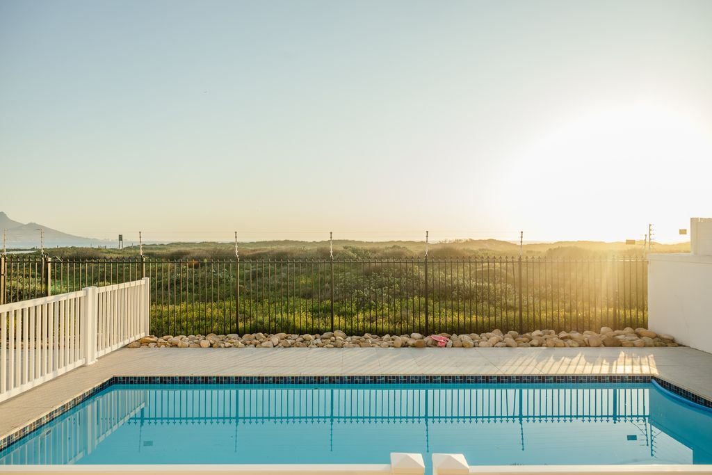 Swimming pool at sunset overlooking a landscape and hills.