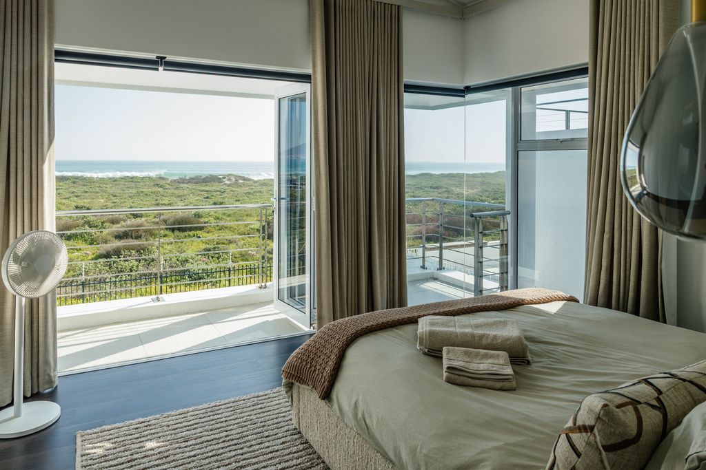 Modern bedroom with balcony view of the ocean and dunes