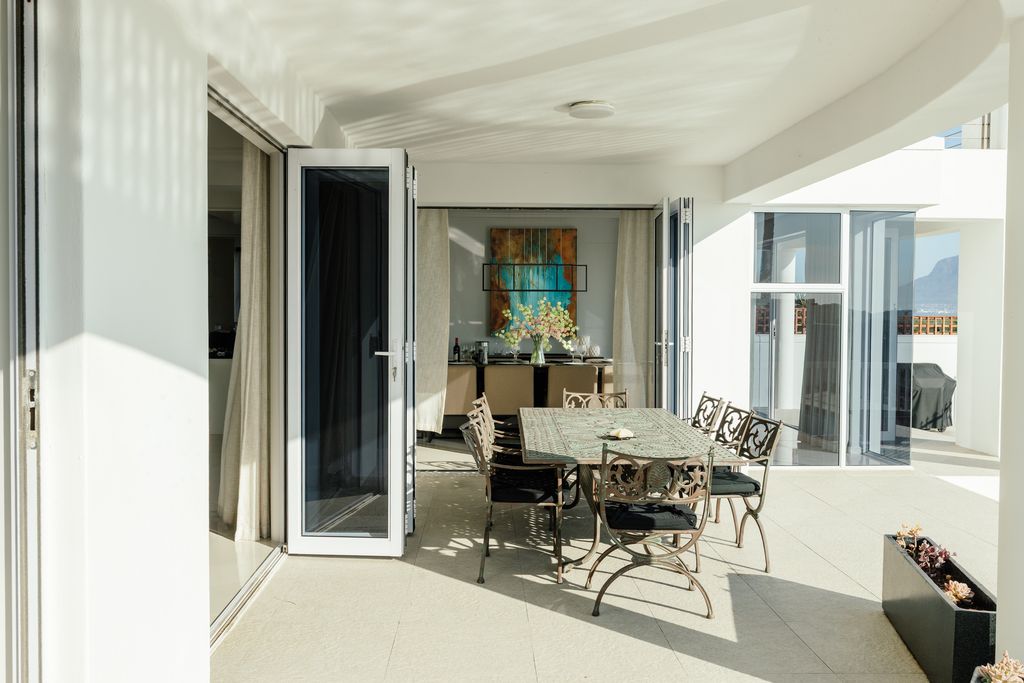 Outdoor dining table on a sunlit white patio balcony.
