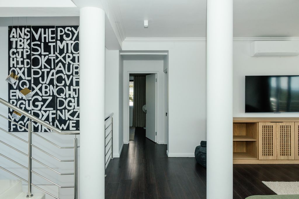 Modern white hallway with dark wood floors and large typography wall art