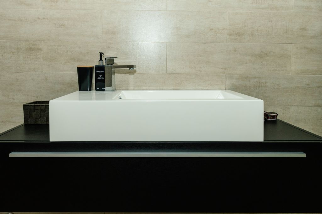 Modern white vessel sink on a black vanity.