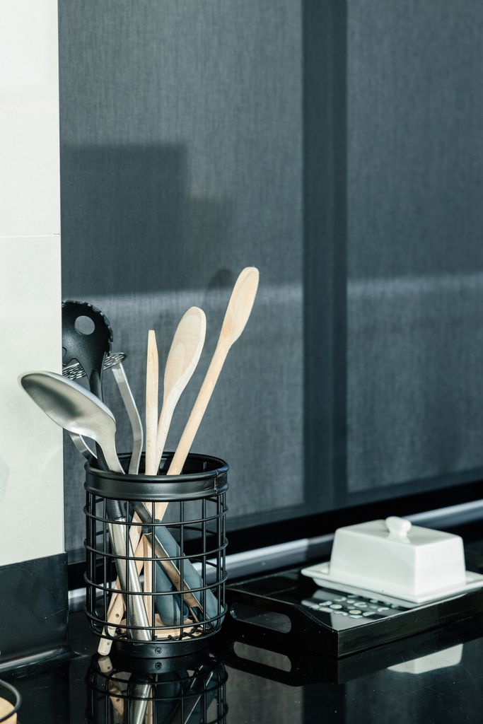 Kitchen utensils in a black wire holder on a counter