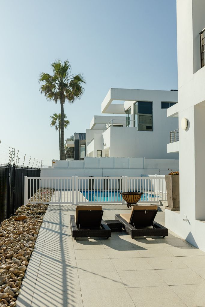 Modern white villa patio with loungers and pool view