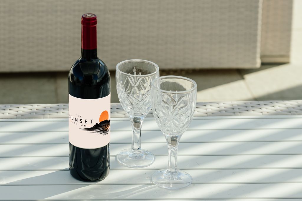The Sunset Edition red wine bottle with two crystal glasses on a white table