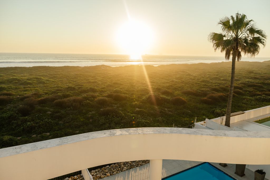 Golden sunset over ocean waves and dunes from a balcony.