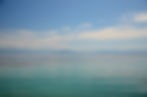 Paysage de mer avec en arrière-plan des montagnes derrière quelques nuages.