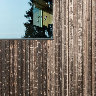 Close-up of façade with glass and shou sugi ban inspired charred and oiled spruce cladding; industrial precision contrasts with hand-worked finish in harmony.