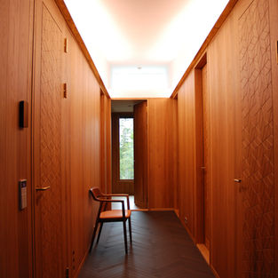 Oak-lined hallway in north bedroom wing with skylight, patterned doors and daylight view beyond.