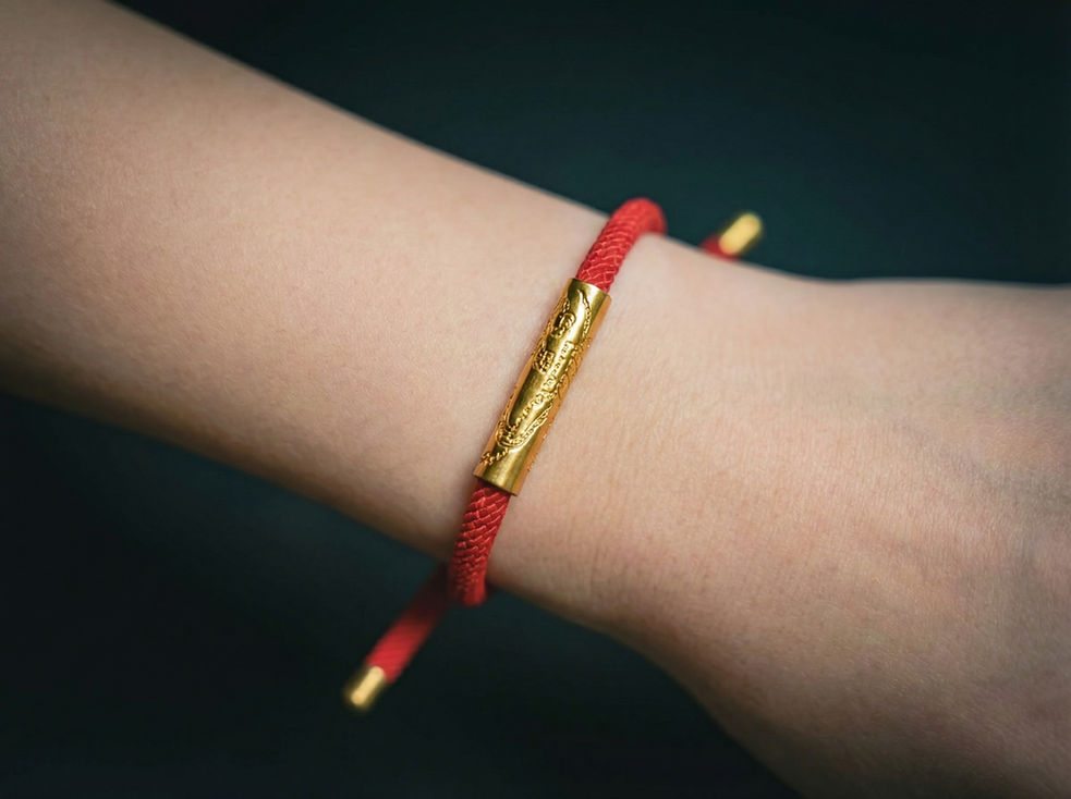 Bracelet cordon rouge avec tube doré sur un poignet