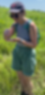 A woman in green shorts and grey shirt holding an insect.