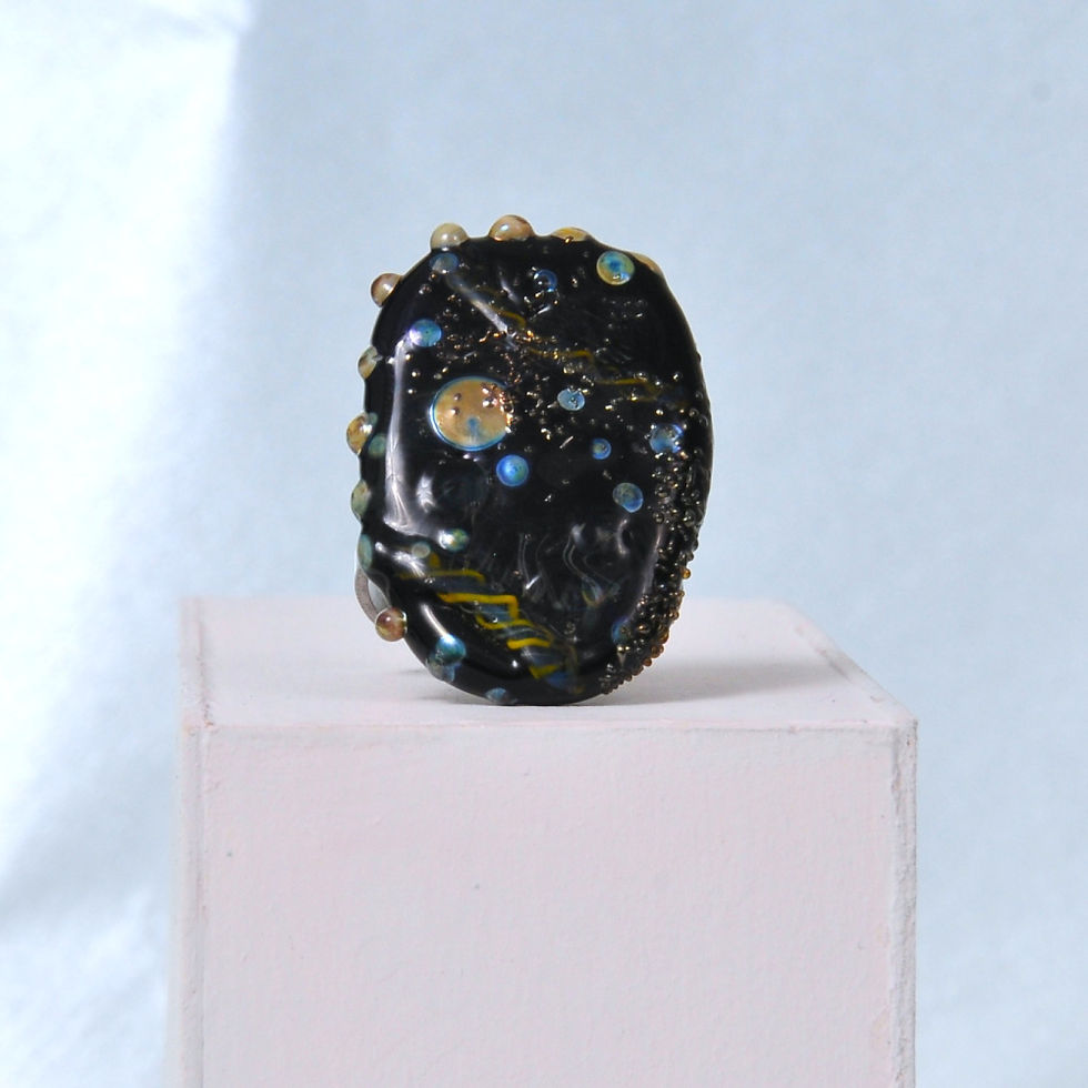 pierścionek z czarnym oczkiem i połyskującymi złotymi zdobieniami