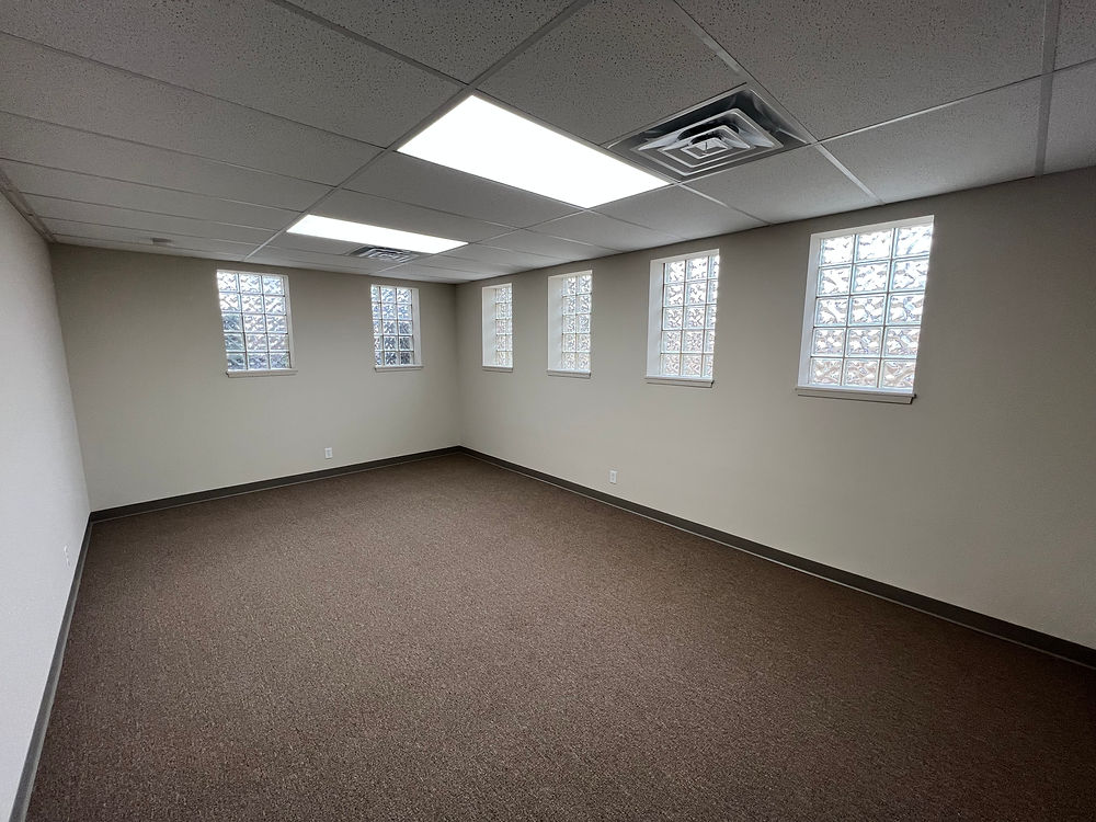 Empty office space for lease, light carpet, small windows