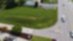 Aerial view of a grassy commercial lot for sale next to a busy road