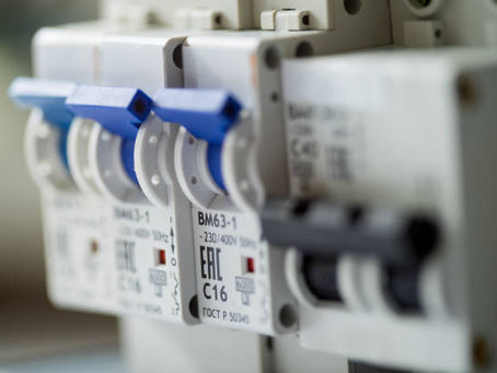 Close-up of electrical circuit breakers with blue switches. Labels display "230/400V" and "C16." Soft lighting, industrial setting.