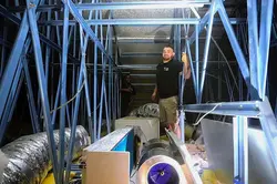 Two Dream Air Conditioning technicians work inside a metal-framed roof space installing a ducted sys