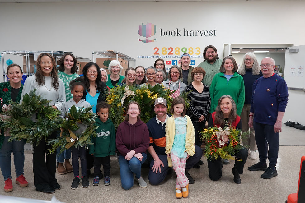 Todos los asistentes a la fiesta posan para una foto de grupo, sosteniendo sus coronas navideñas. Hay más de 20 personas presentes.