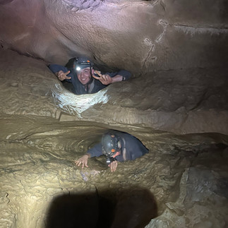 Caver navigating a narrow belly crawl during the Wild Cave Tour