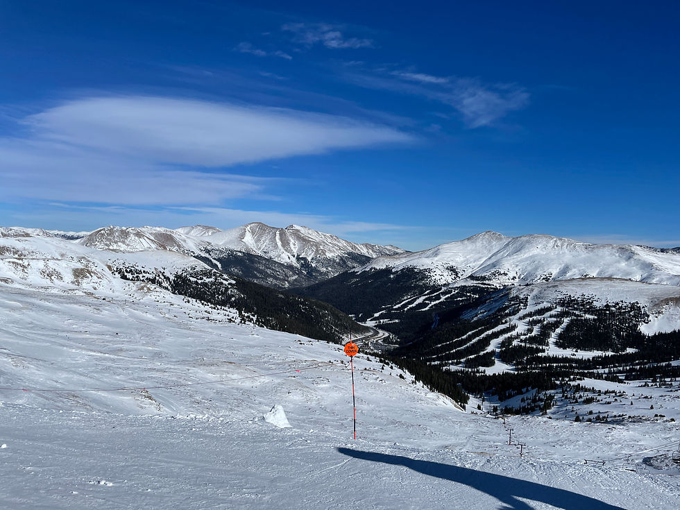 Snowy mountain ski slope under a clear blue sky, with an orange Thin Cover warning sign above a valley.