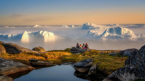 Family enjoying a Bespoke Greenland adventure, overlooking icebergs at sunset on a boutique Arctic experience.