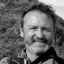 Portrait of Lars Ranthe, Oscar Award-winning actor, smiling outdoors with rugged nature in the background.