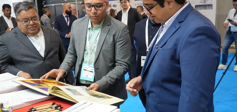 Men reviewing documents, at a conference, Yash Showcases Innovation and Strengthens Global Presence