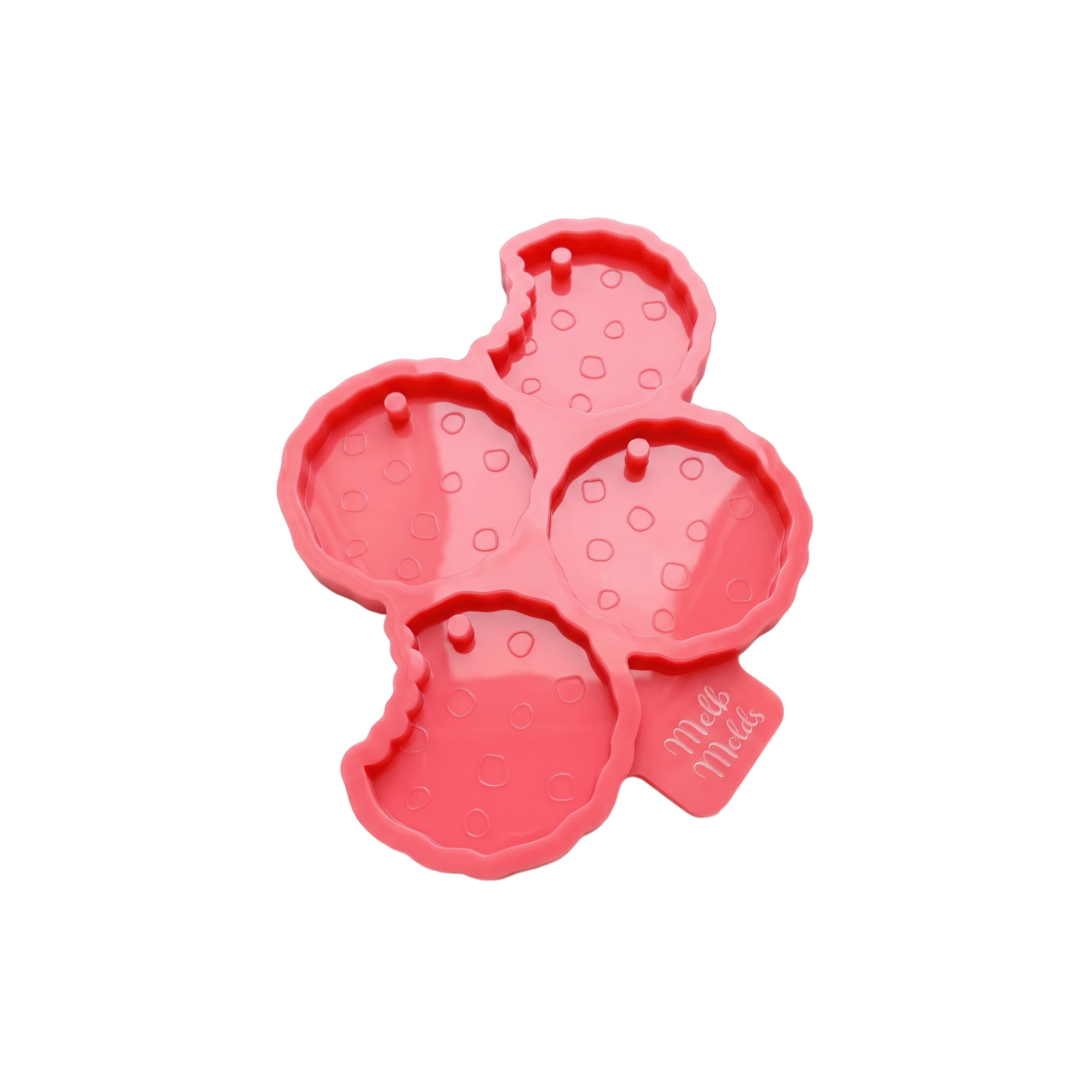 Pink silicone mold with four chocolate-chip cookie-shaped tag cavities, including two with bite marks, and hole-forming pins.