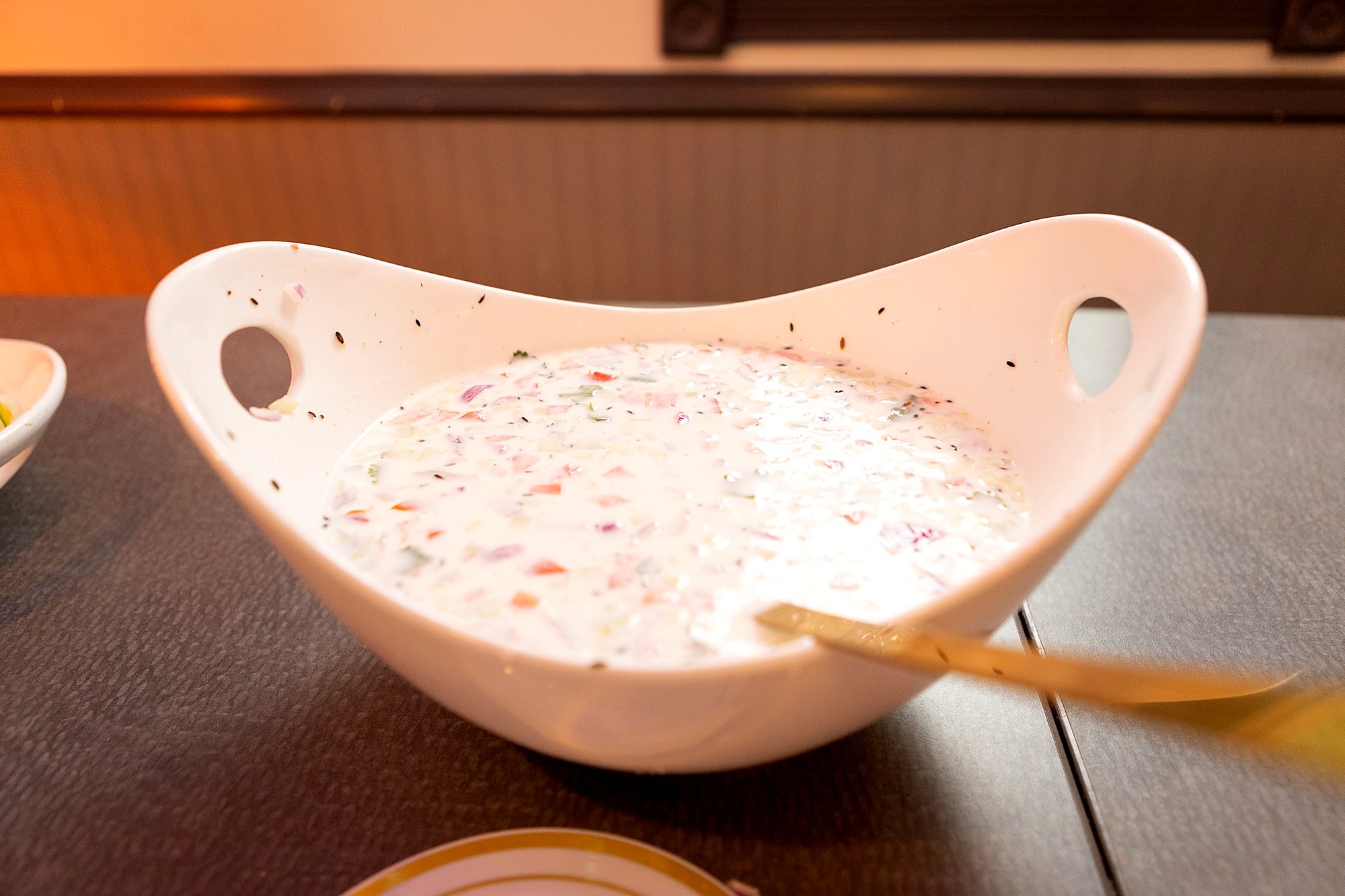 Cool cucumber, onion and tomato raita in a white serving bowl