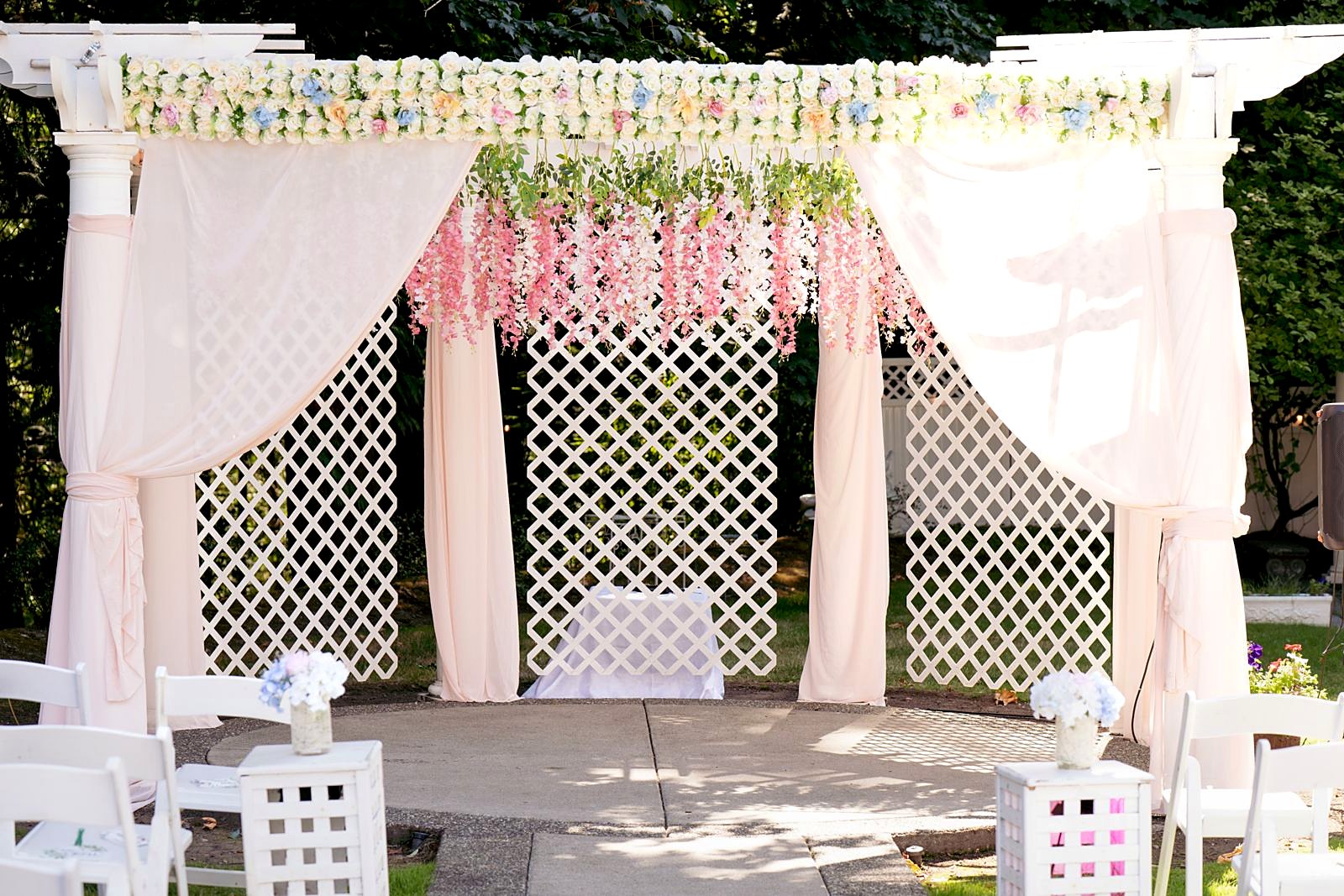 Pergola dressed with wisteria and white drapes for a ceremony