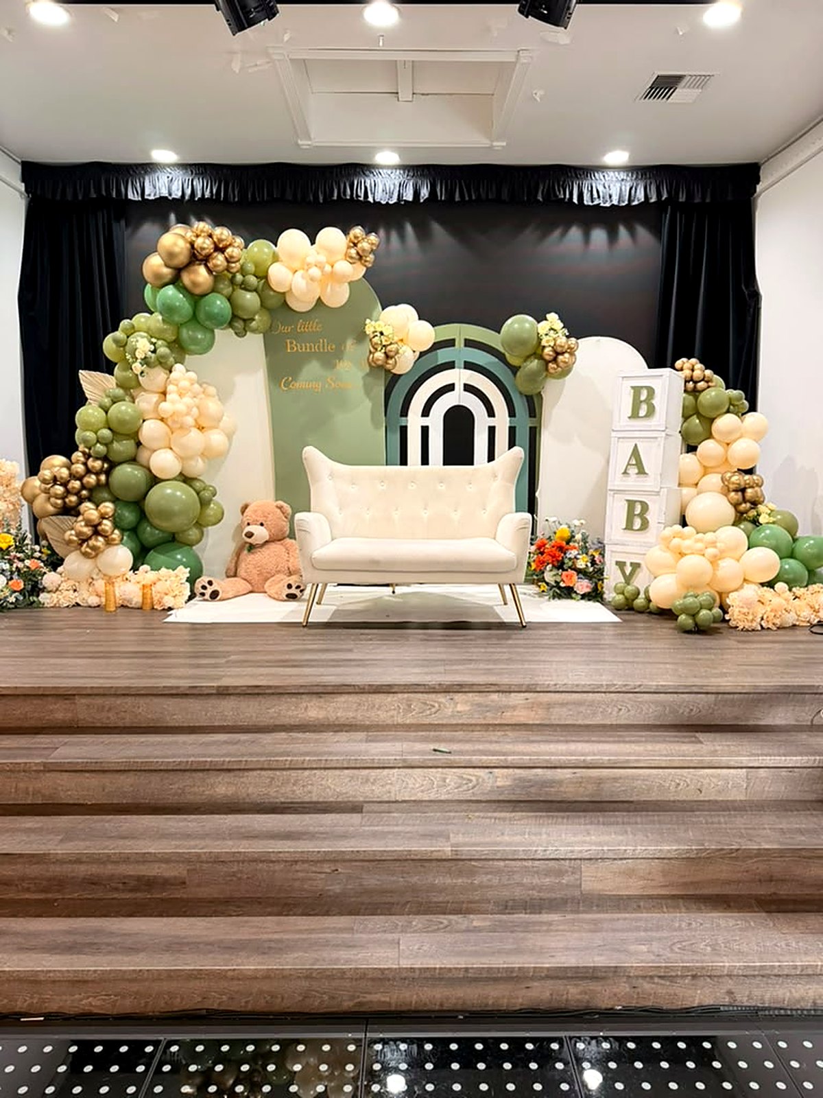 Sage, ivory and gold baby shower stage – “Bundle of joy” arch panels, BABY blocks, teddy bear and white loveseat