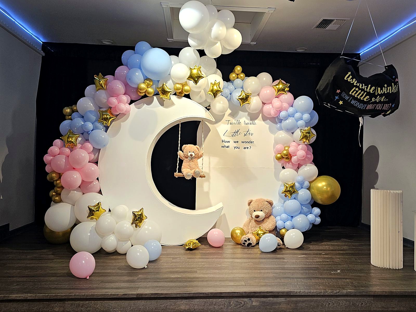 Crescent-moon stage with pink, blue and gold balloon garland, stars and teddy bears