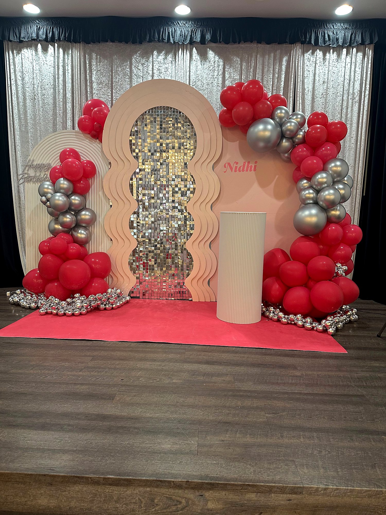 Red and silver birthday backdrop – wavy blush arch with silver shimmer wall, “Happy Birthday” sign and disco balls