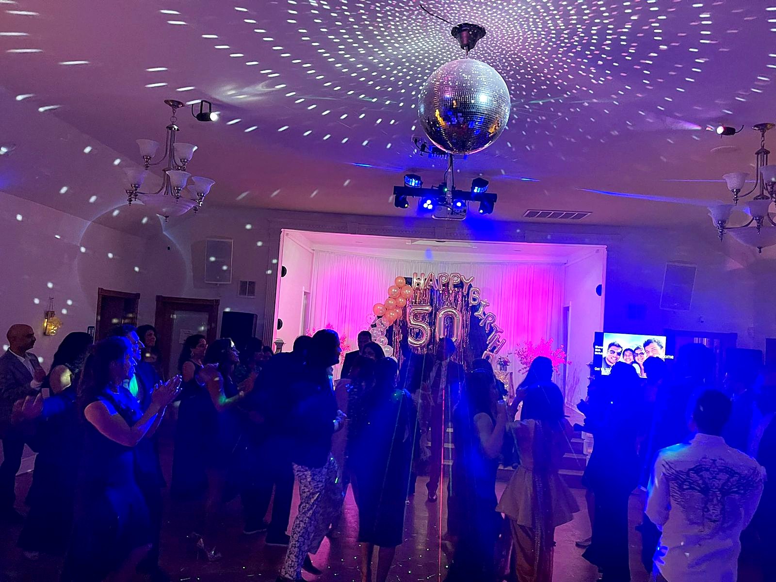Packed dance floor under the disco ball and party lights