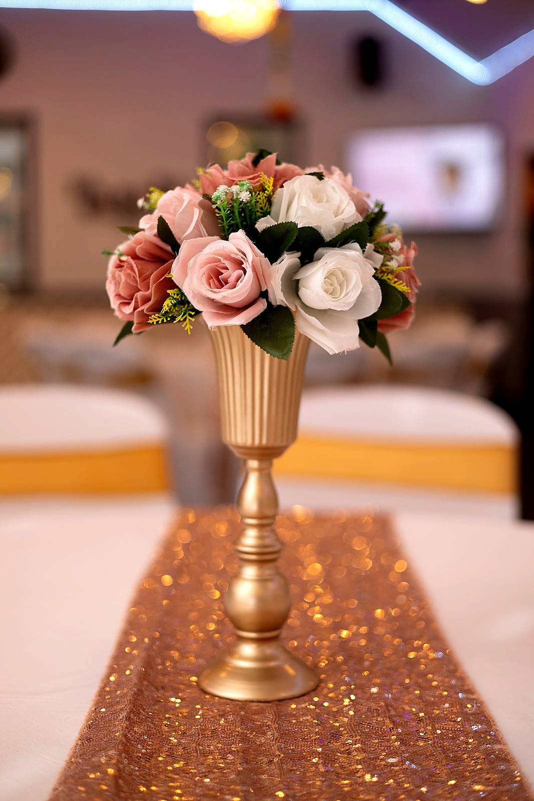 Blush and white roses in a fluted gold vase on a rose-gold sequin runner