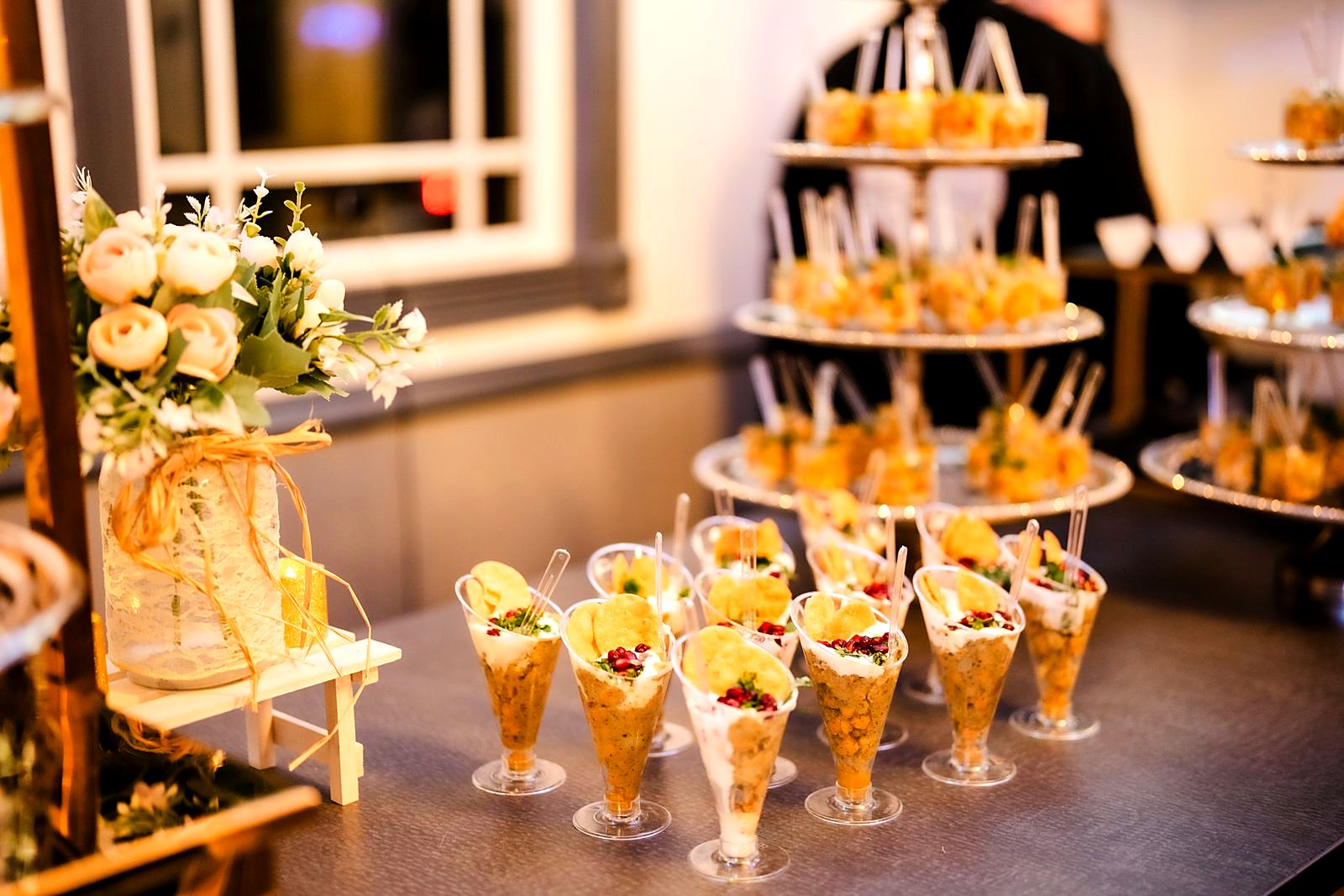 Chaat cup station beside silver tiered stands and a lace-wrapped floral jar