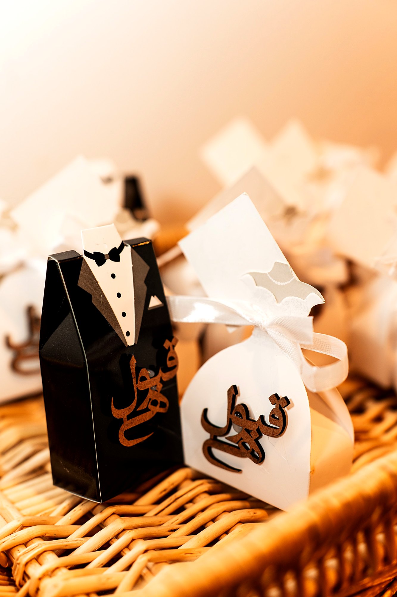 Bride-and-groom nikkah favor boxes with carved calligraphy, set out in a wicker basket