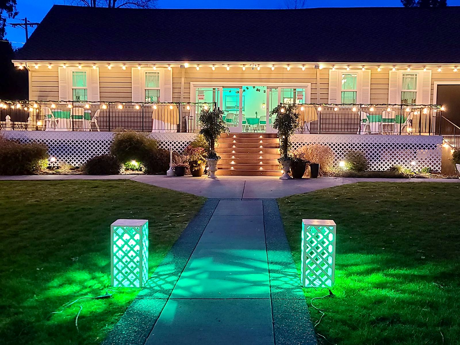 The manor at night – string lights along the deck and glowing lattice lanterns lining the garden path