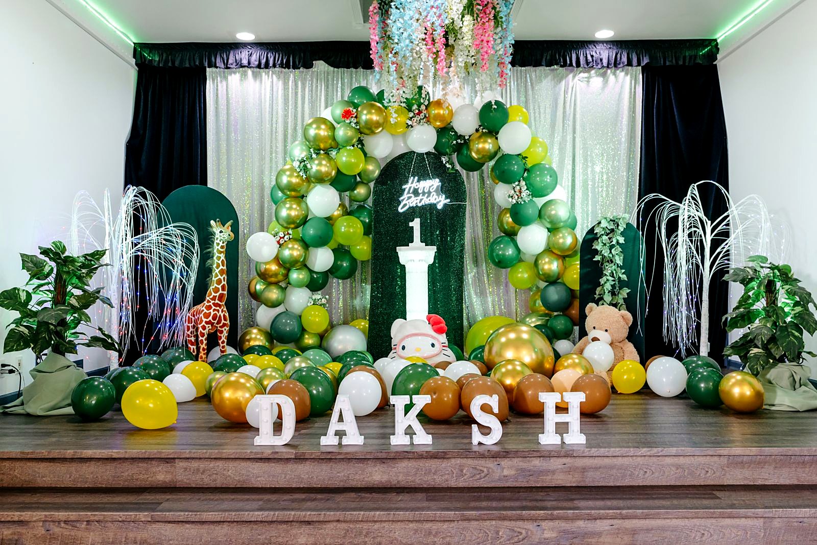 Jungle-themed 1st birthday stage with green and gold balloons