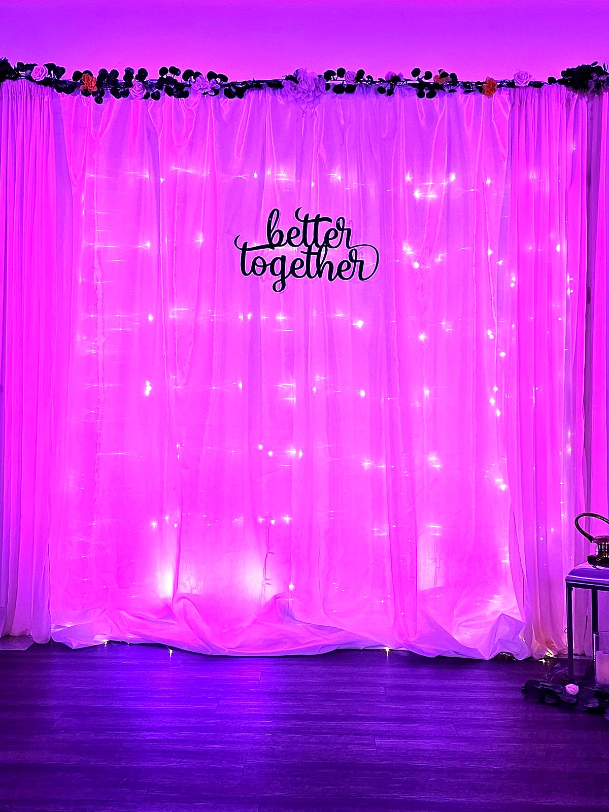 Sheer draped backdrop with fairy lights and a "better together" sign under pink uplighting