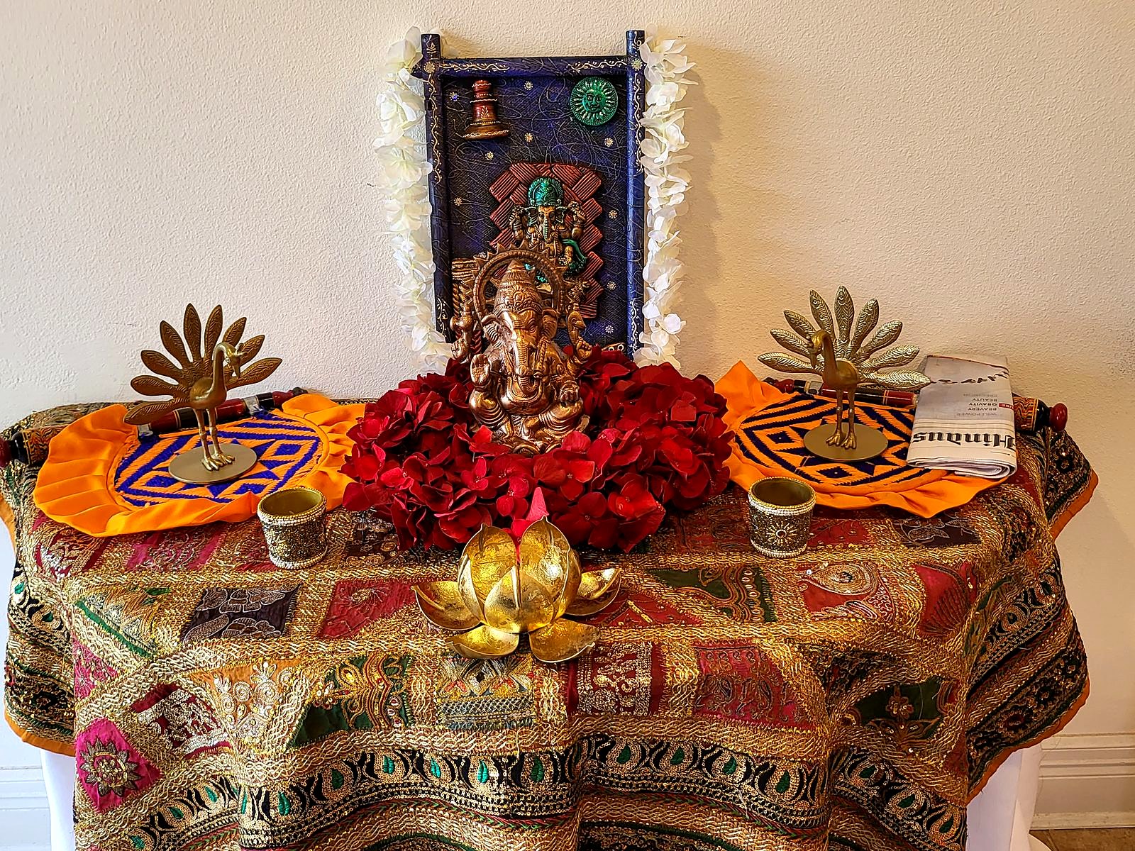 Ganesha altar on an embroidered patchwork cloth with brass peacocks and a gold lotus