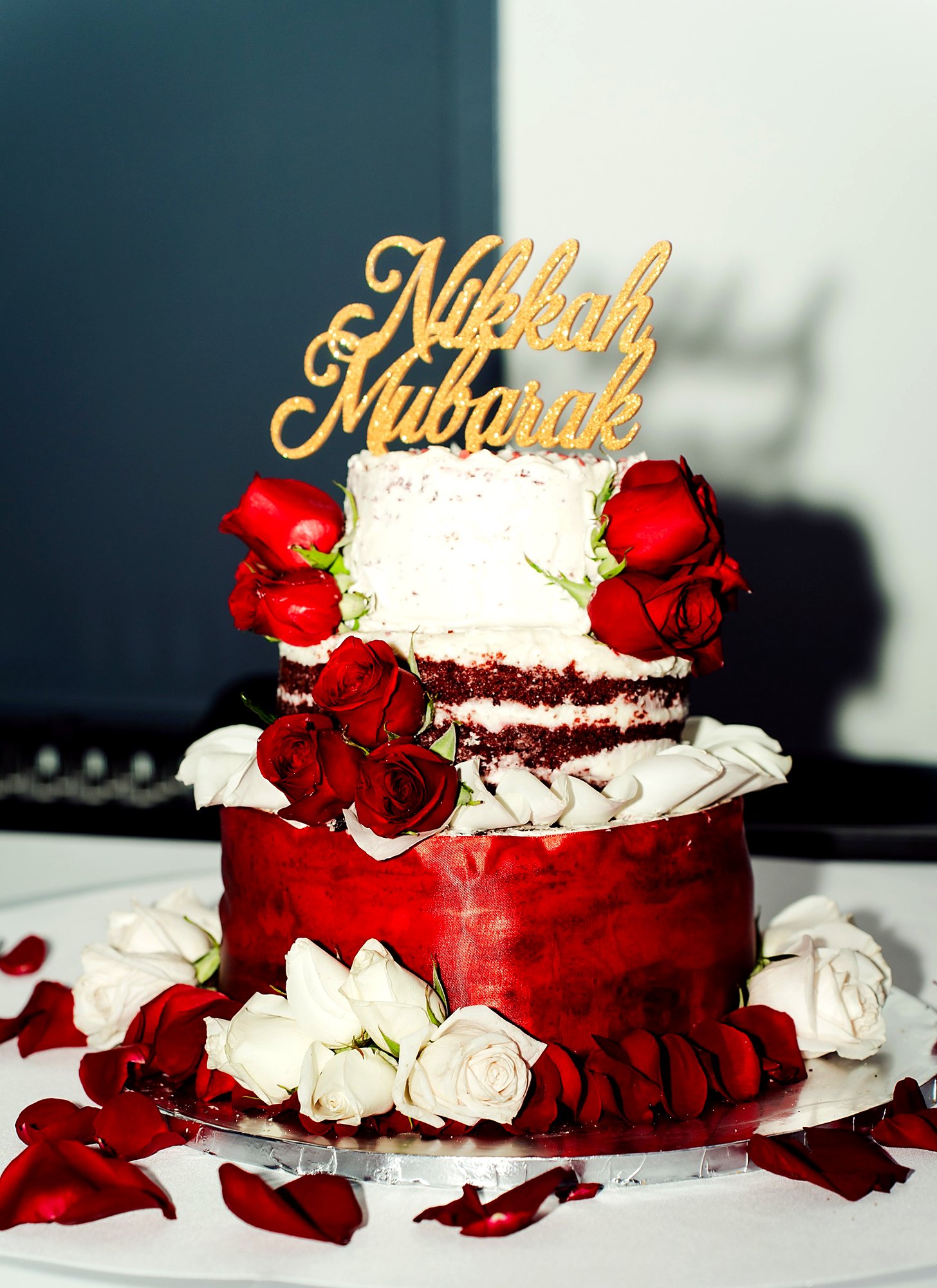 Nikkah cake – red velvet tiers dressed with fresh red and white roses under a gold "Nikkah Mubarak" topper