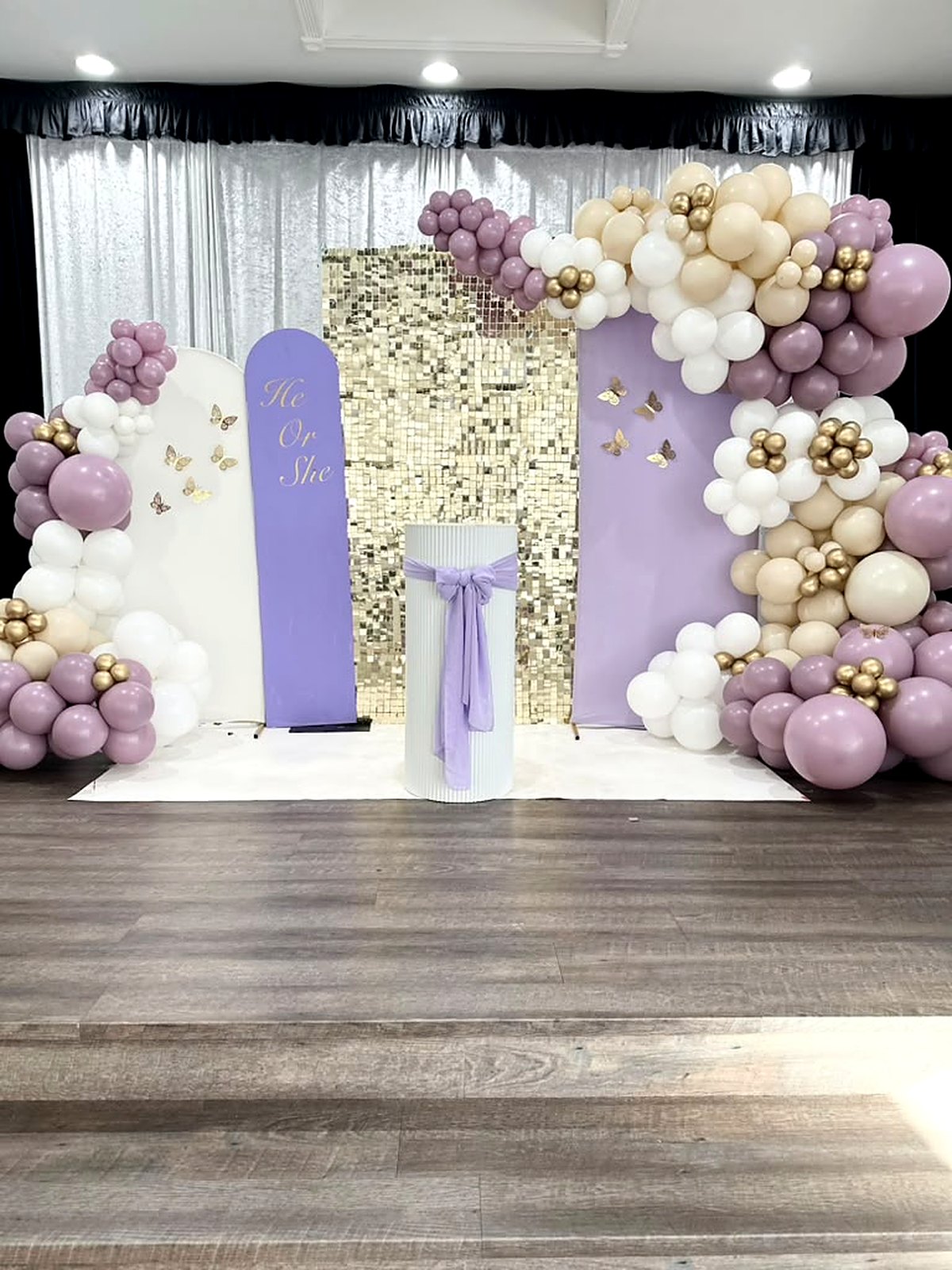 “He or She” gender reveal backdrop – lavender and white arches, gold shimmer wall and mauve, ivory and gold balloon garland