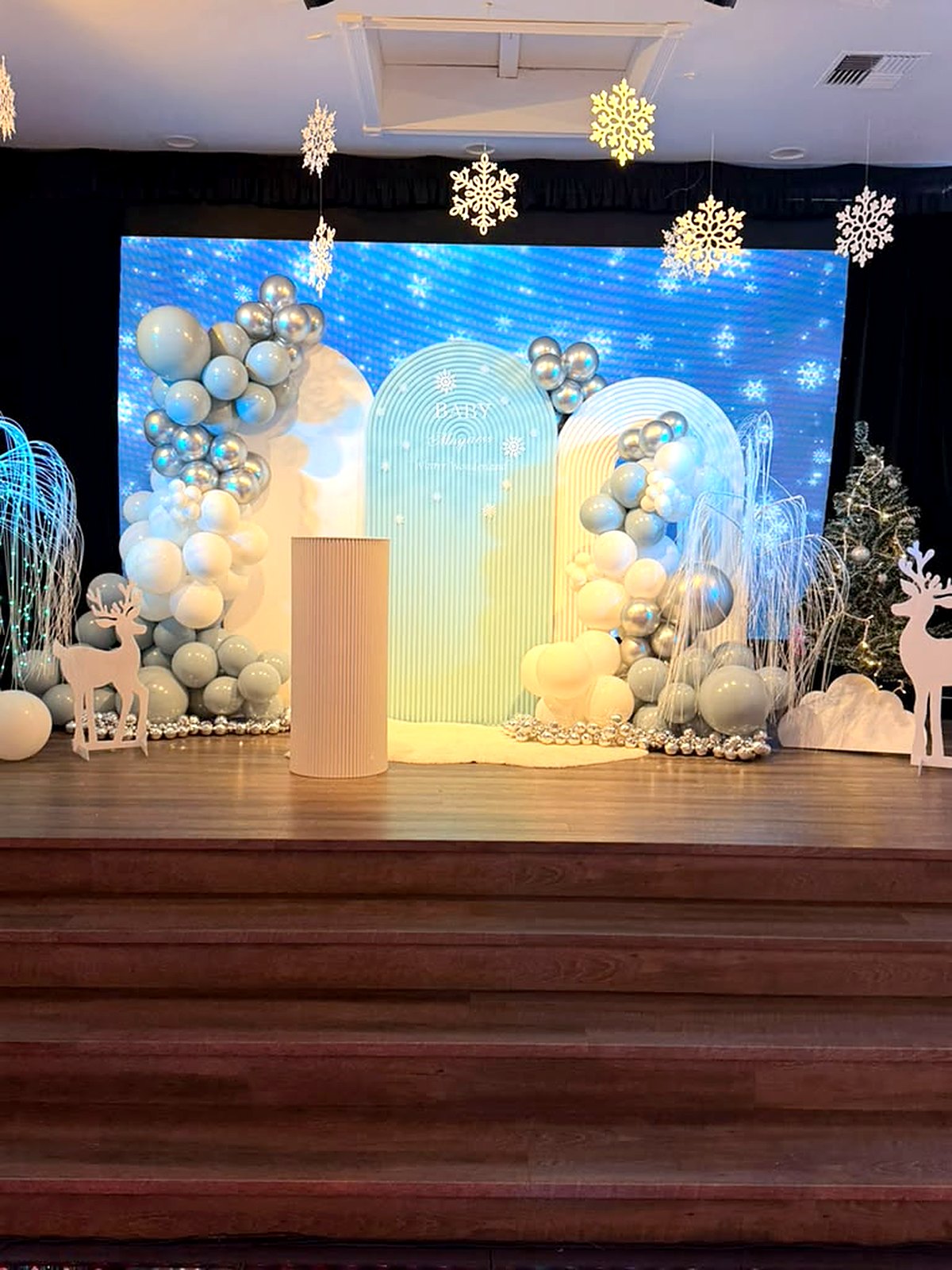 Winter wonderland baby shower – snowflake LED wall, frosted arches, silver and sage balloons and white reindeer