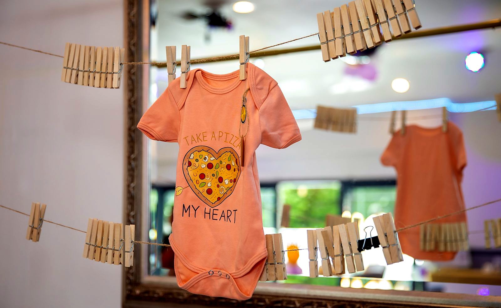 "Take a pizza my heart" onesie on a clothespin line – a baby shower activity station