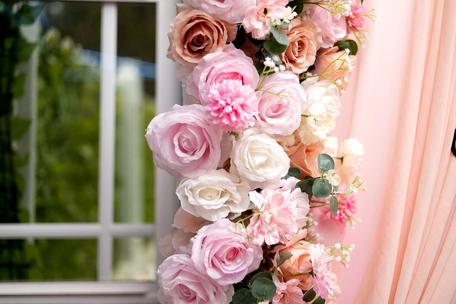 Close-up of a blush, ivory and peach rose garland against peach drapes