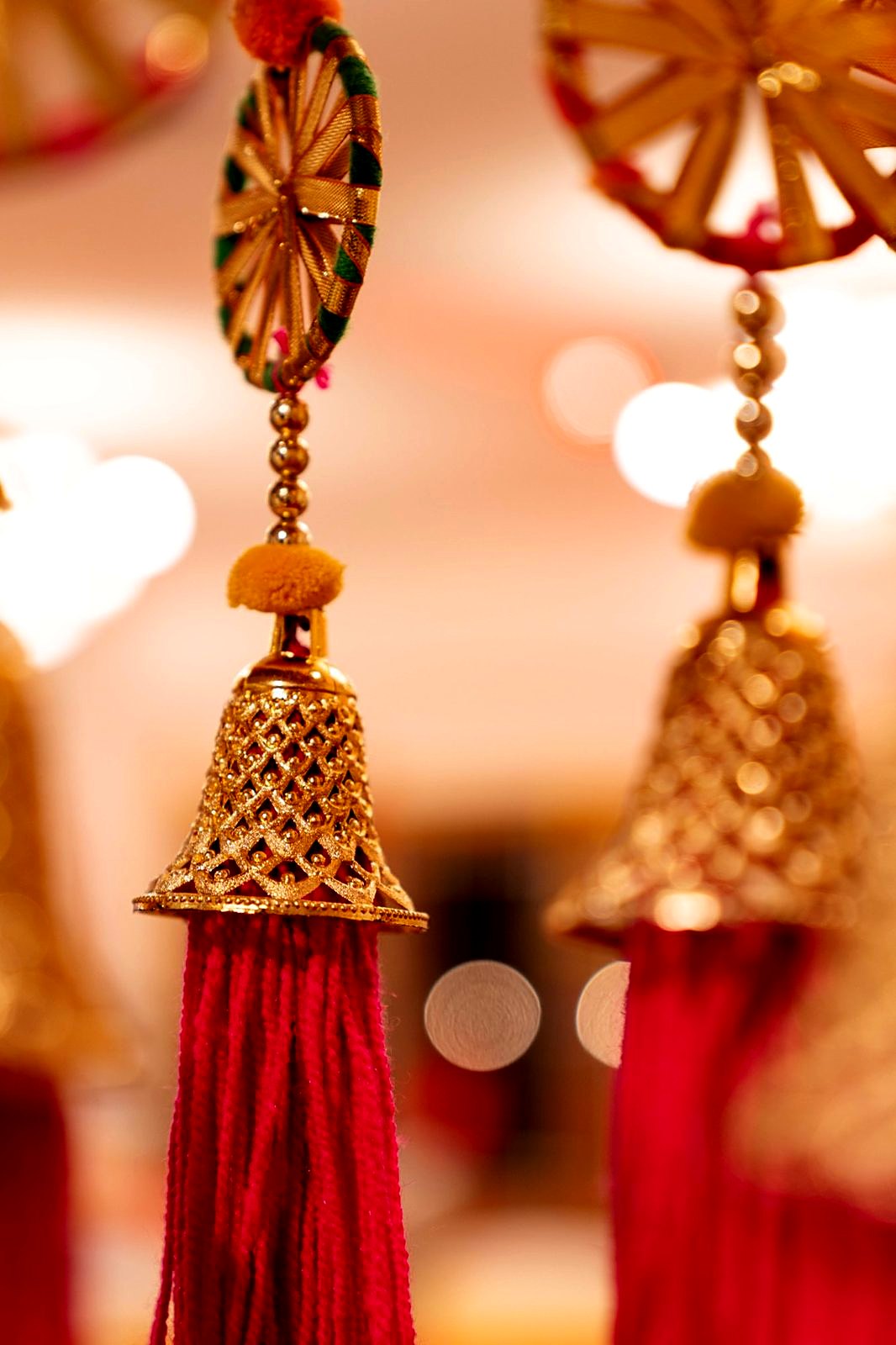 Gold bell tassels with fuchsia threads hanging from the mandap