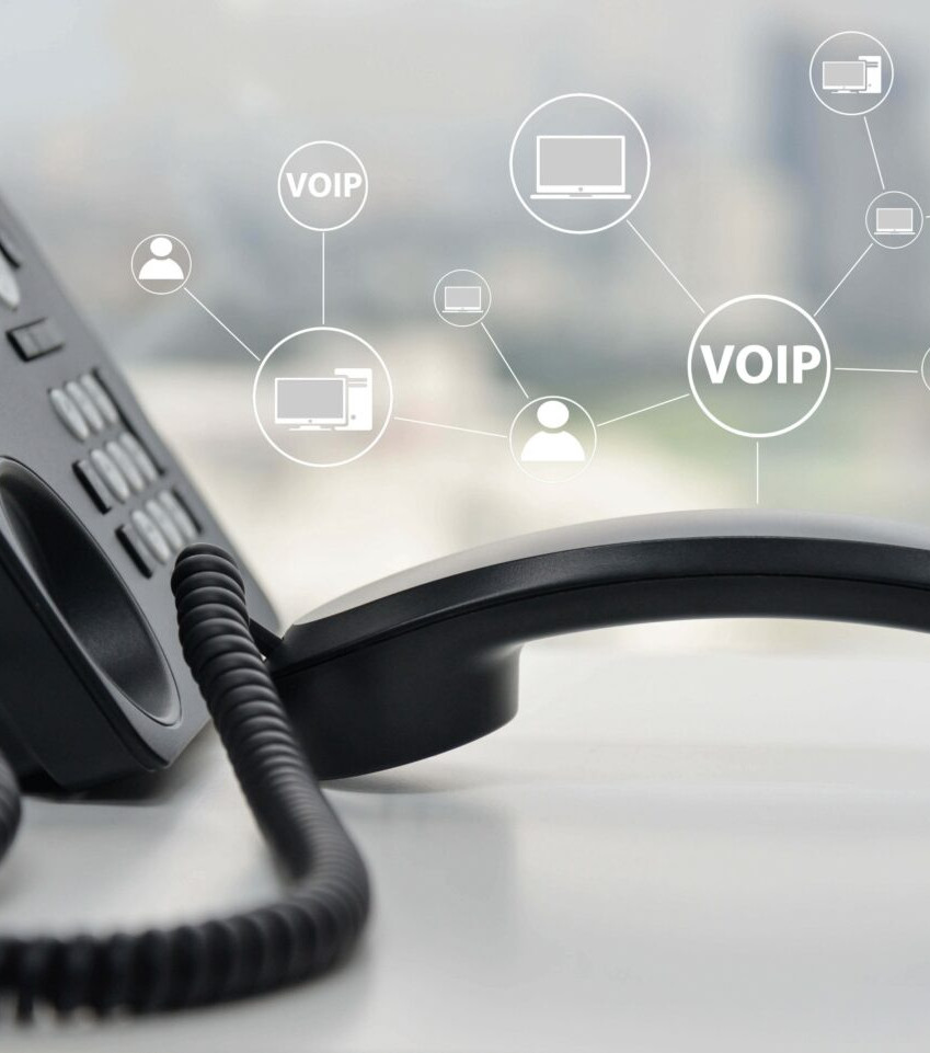 Black office phone handset on desk with VOIP network icons over a blurred office background