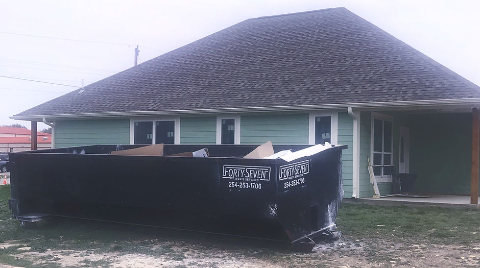 roll off dumpster partially full of trash in front of new home under construction